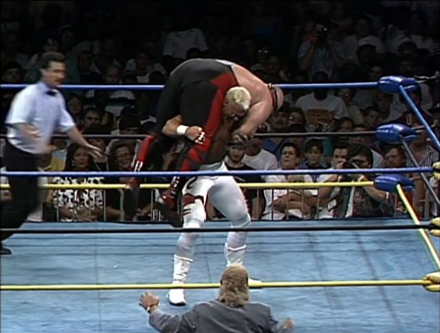 Sting braces beneath Vader, supporting him across his shoulders before the slam.